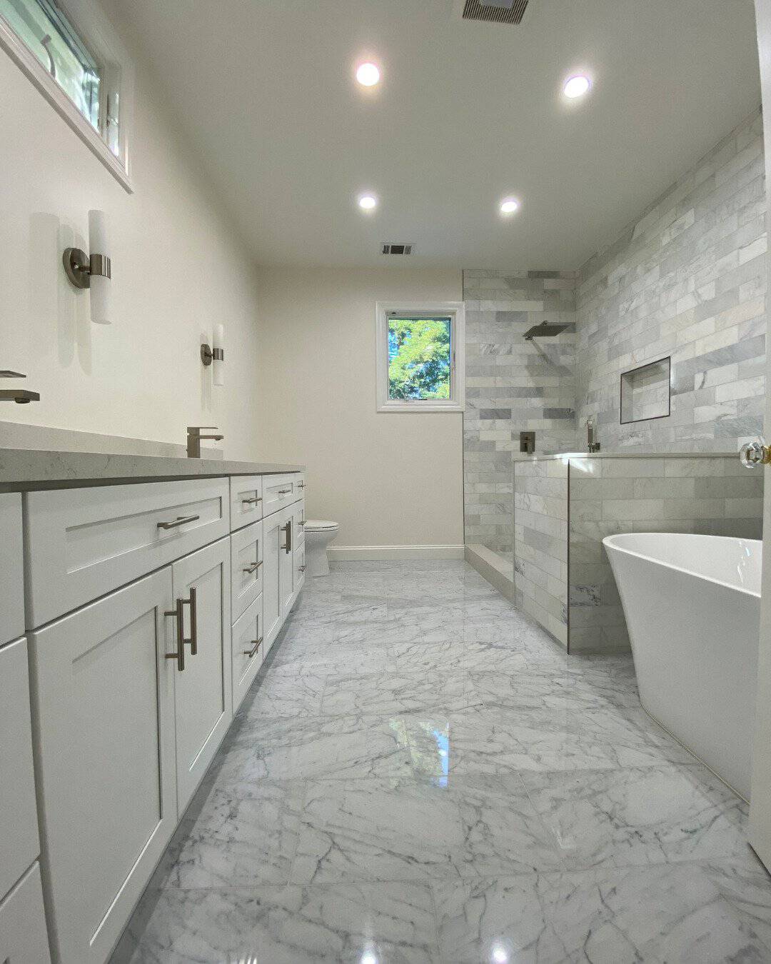 Luxury master bathroom remodel in San Carlos, CA featuring polished marble floor tiles, a white double vanity, a freestanding soaking tub, and a walk-in shower with marble tile surrounds.
