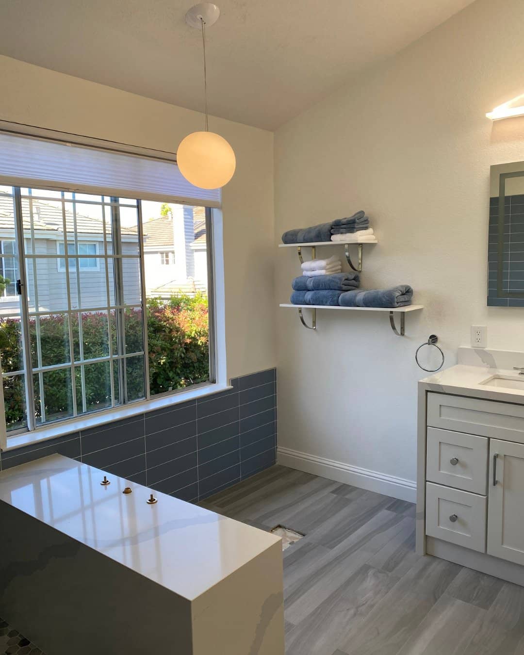 Modern bathroom remodel in San Carlos, CA featuring blue subway tile wainscoting, a white vanity, and a custom soaking tub.
