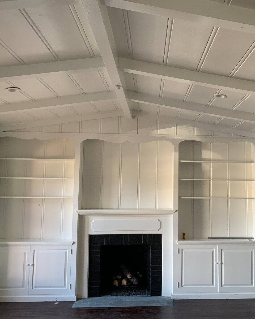 Custom white fireplace surround and built-in bookshelves with a vaulted beamed ceiling in San Carlos, CA.